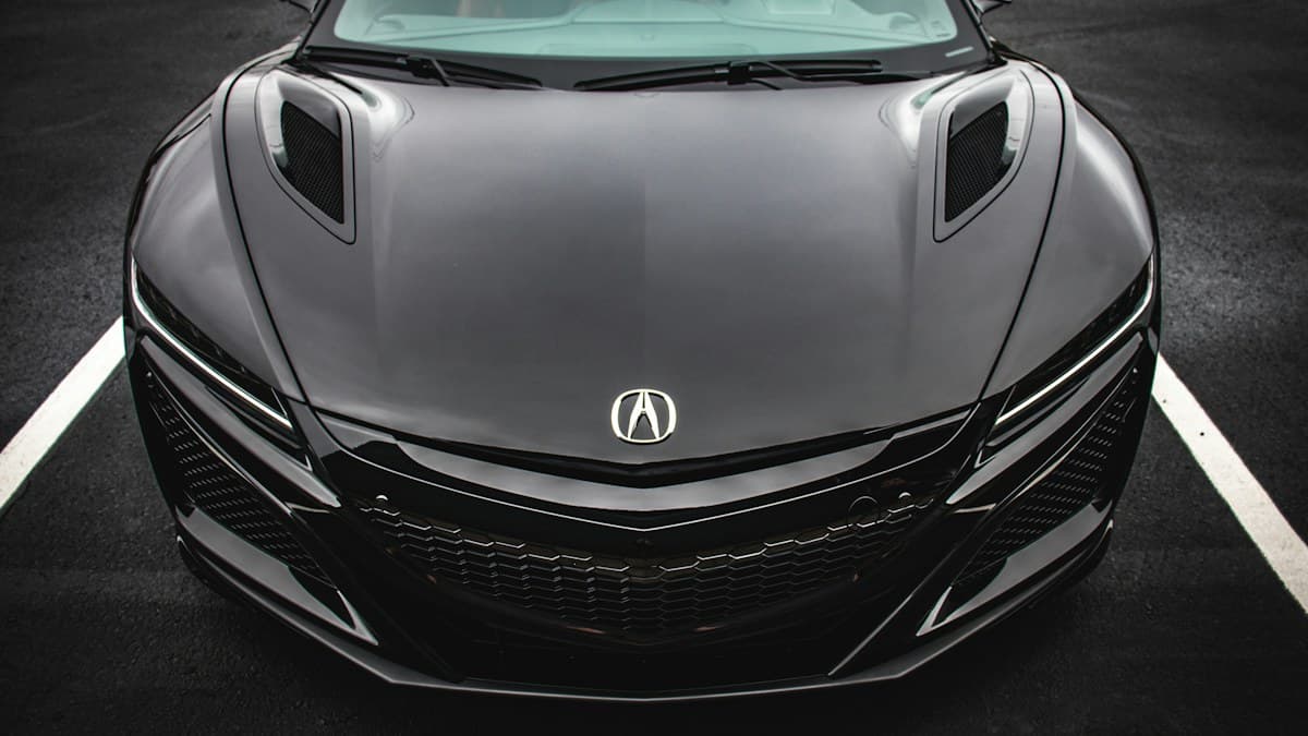 Photo: Tory Bishop / Unsplash Front of a black second-generation Acura NSX parked between white road markings. The brakes are not visible.