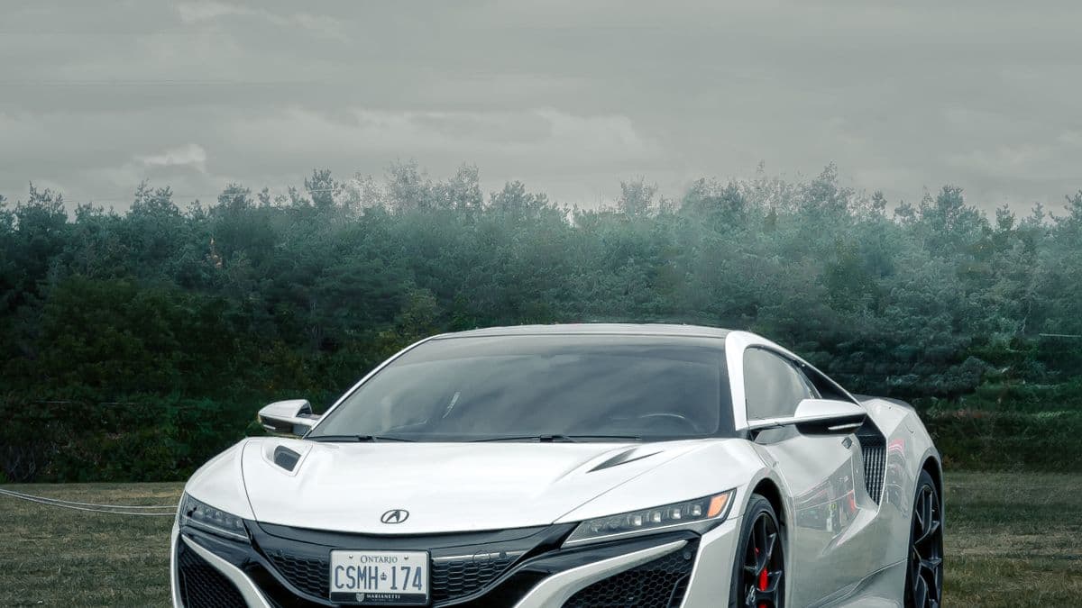 Photo: cjh_optics / Pexels White second-generation Acura NSX parked beside a treeline.