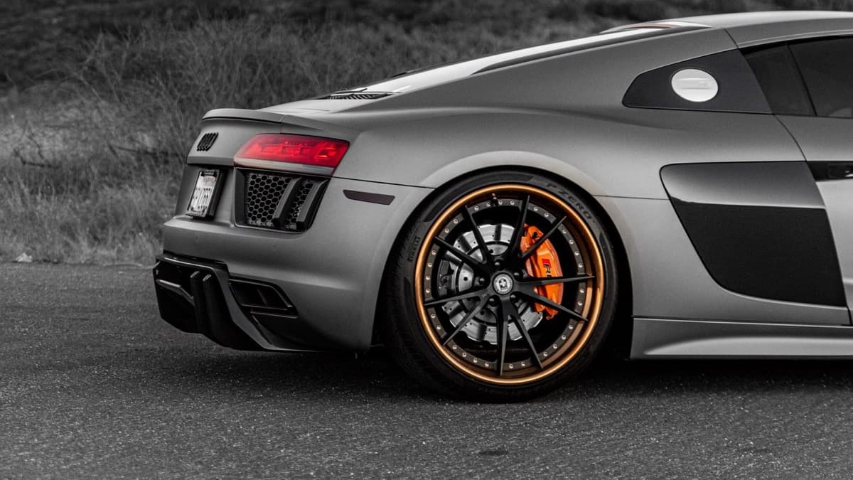 Photo: Tyler Clemmensen / Pexels Rear wheel and side of a gray first-generation Audi R8 parked outdoors.