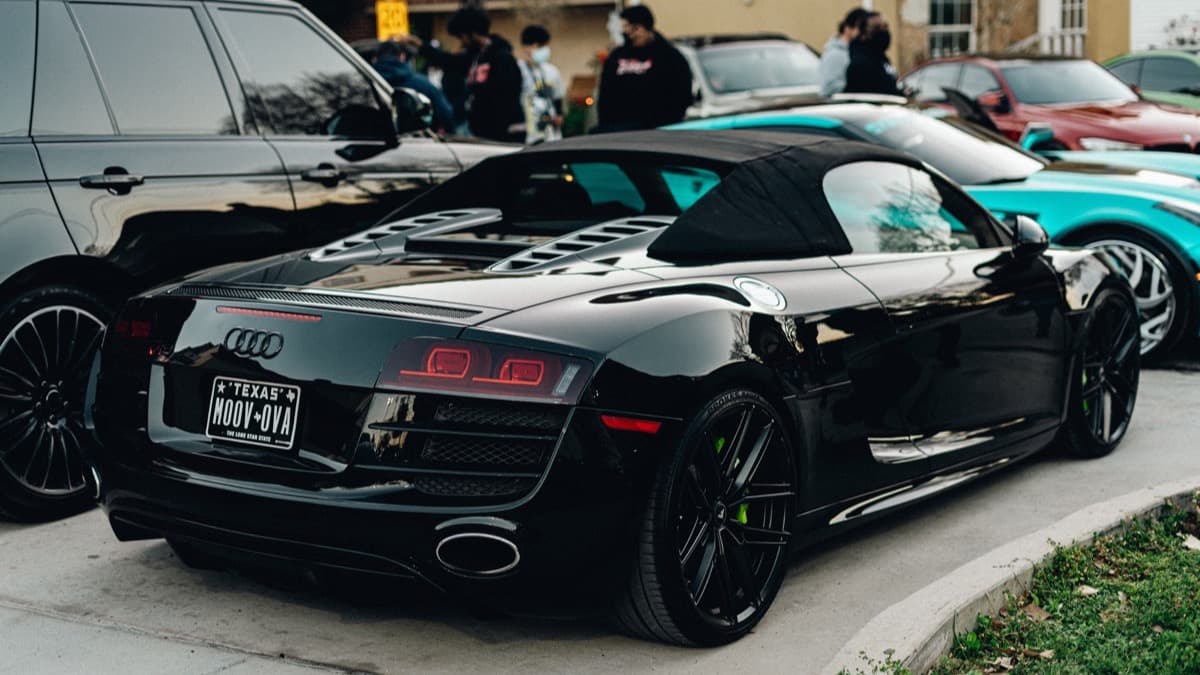 Photo: Adrian Newell / Pexels Black first-generation Audi R8 Spyder with its fabric roof raised at a car gathering.