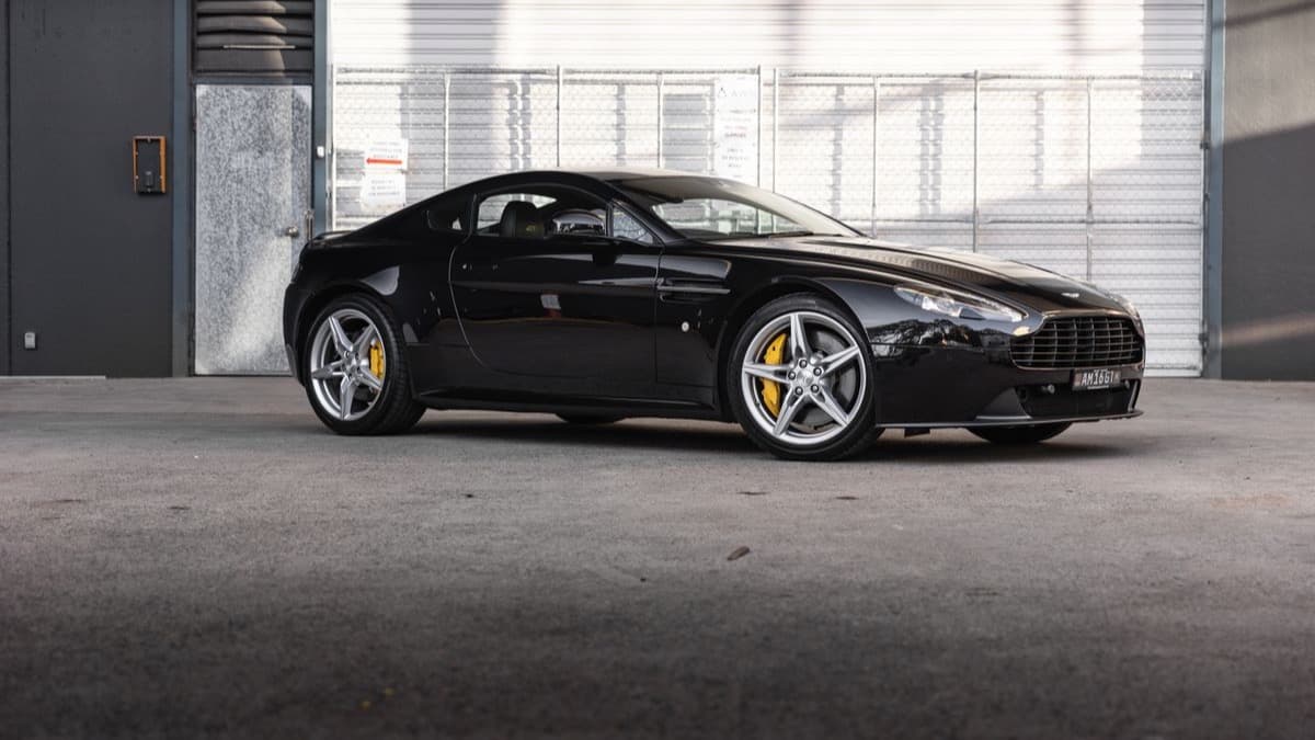Photo: Raimundo Campbell / Pexels A black Aston Martin V8 Vantage parked outside.