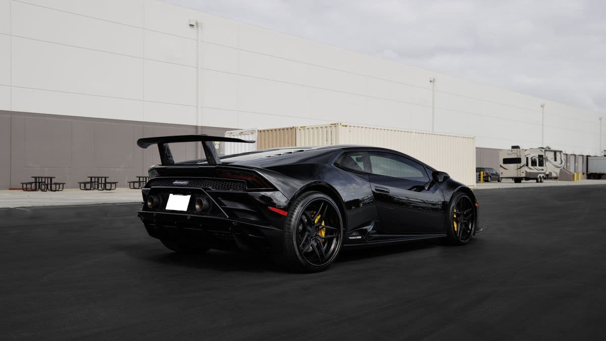 Black Lamborghini Huracán parked outside an industrial building.
